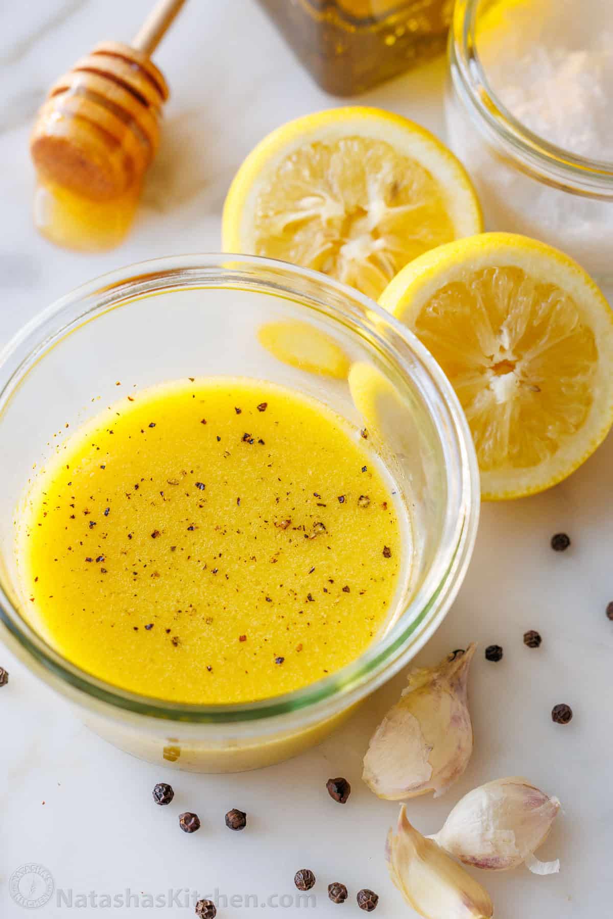 jar of easy lemon vinaigrette salad dressing garnished with pepper and surrounded by fresh ingredients